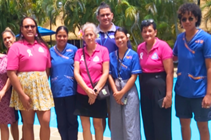 A group of Cook Islands people in pink shirts standing next to a pool