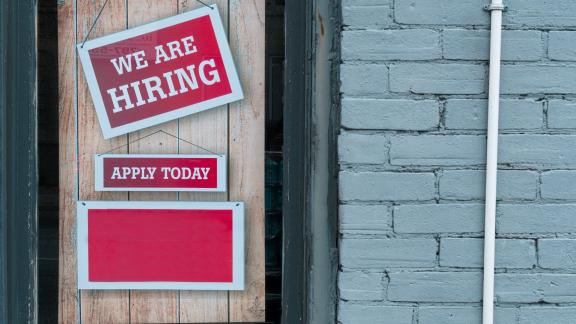 A window sign displaying "We Are Hiring". 